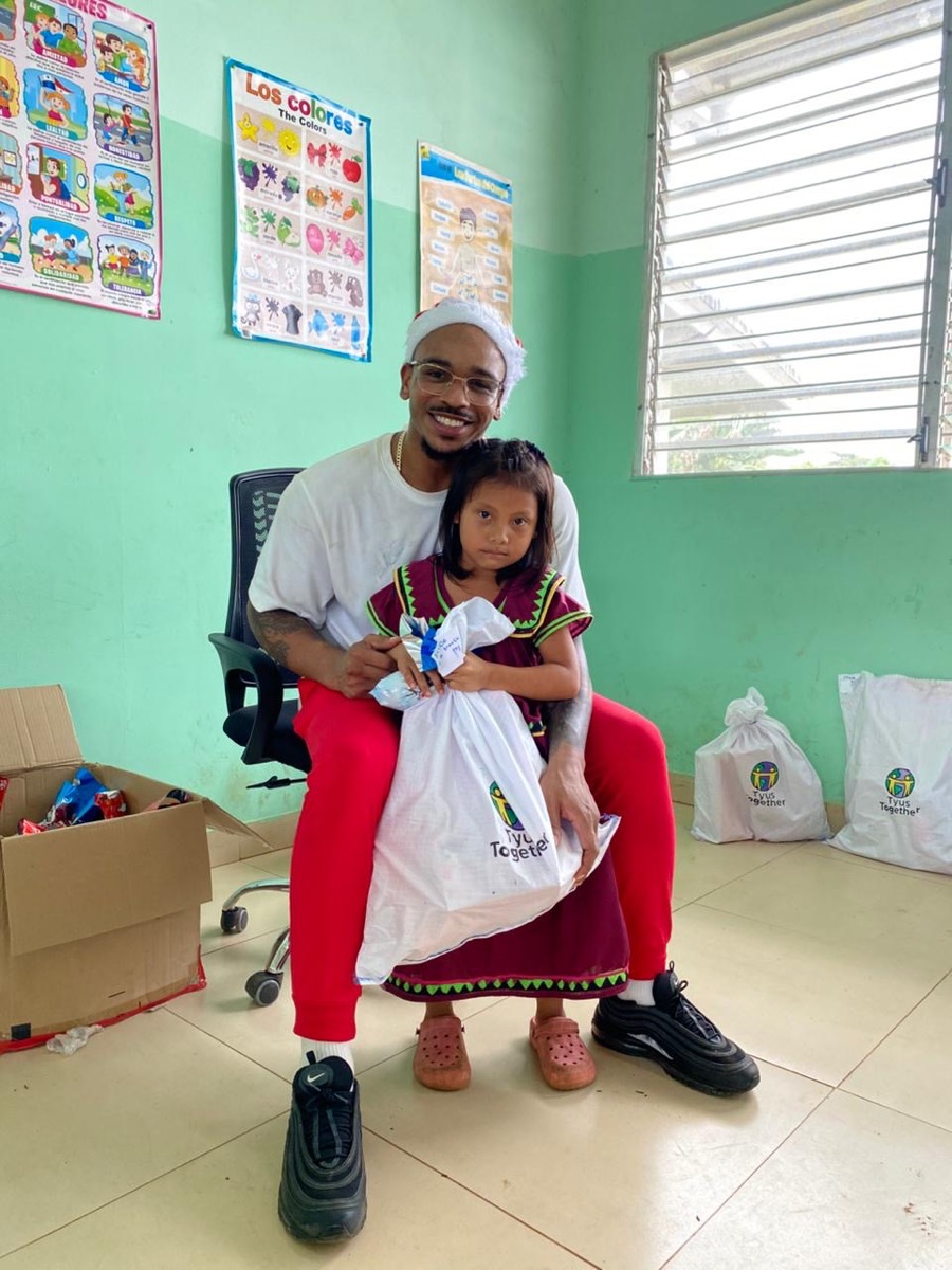 A child in traditional dress receiving a Tyus Together gift bag